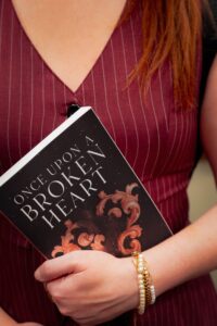 Woman in stylish fall outfit holding book, showcasing autumn fashion vibes.